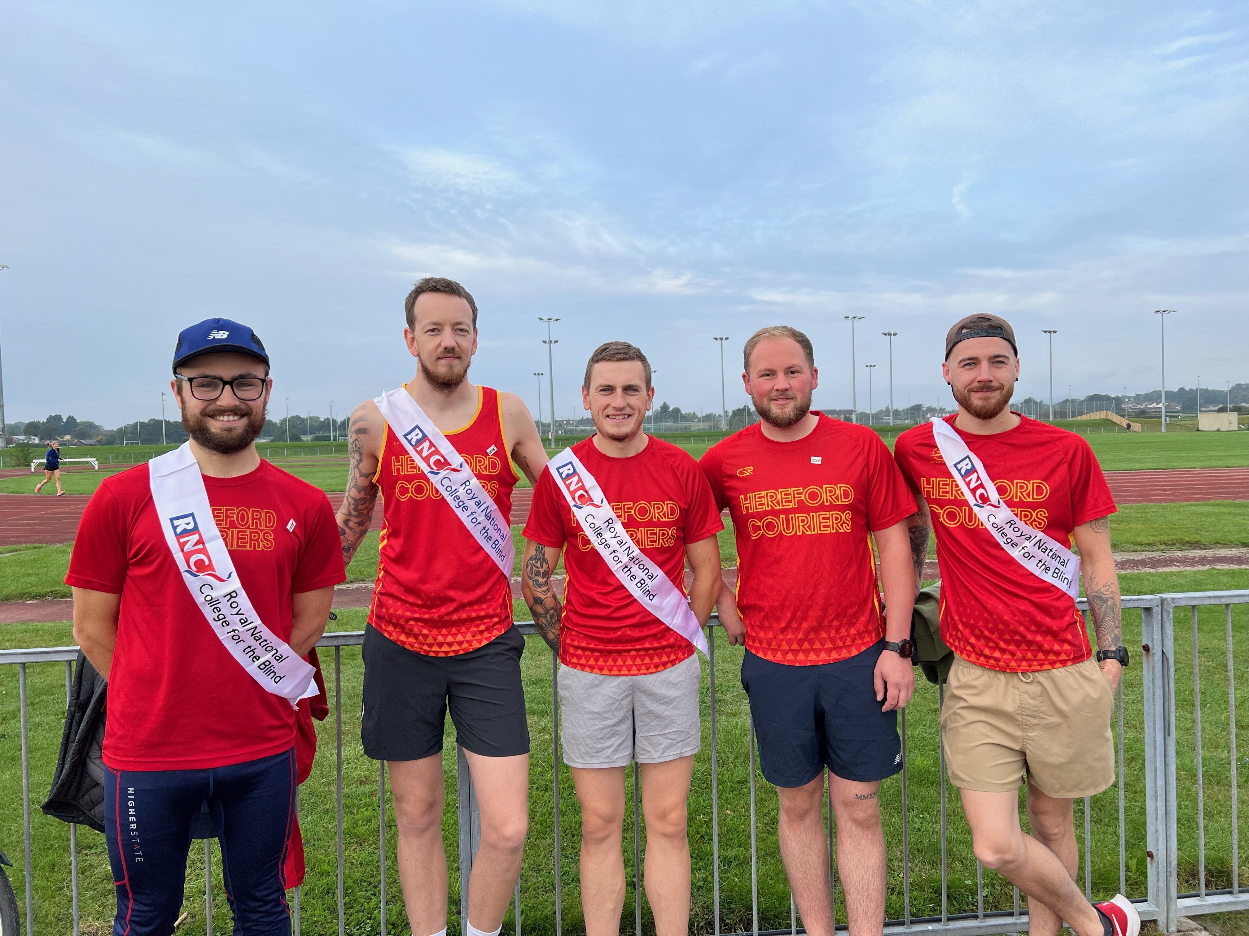 Five of the Hereford Couriers stand together in red courier t-shirts and wearing RNC sashes